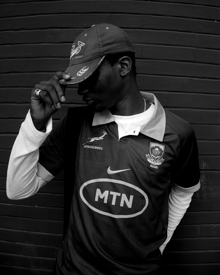 Black and white portrait of a man in a rugby shirt and cap.